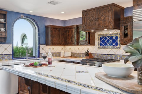 Fully equipped kitchen with stainless steel appliances, a sleek kitchen island, ample counter space, and a gas fireplace.