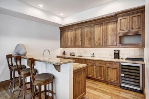 Convenient kitchenette with bar seating, wine fridge, and rustic wood cabinetry—perfect for evening cocktails.