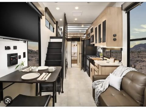 Bright, modern interior with full kitchen, cozy seating area, and loft bedrooms above.