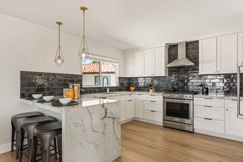 Sleek modern kitchen with marble waterfall island, stainless steel appliances, and chic black tile backsplash—perfect for gathering and entertaining.