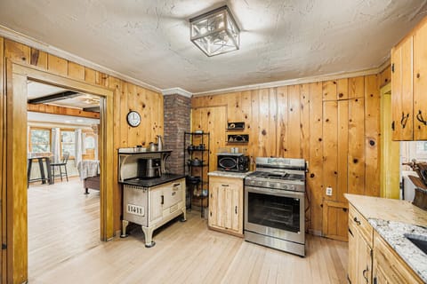 Antique wood-burning stove adds rustic flair next to full modern appliance suite.