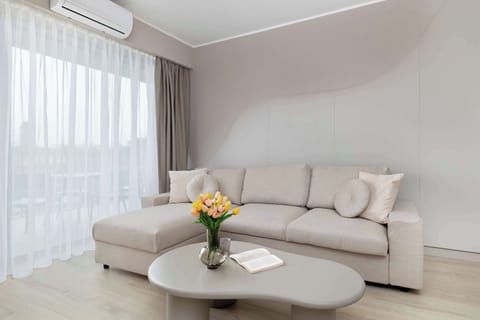 Bright living room with a soft beige sofa, round coffee table, and large window.