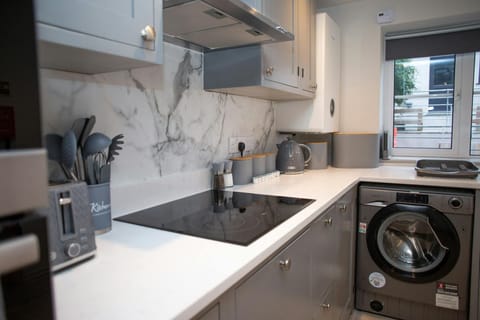 Close up of kitchen with hob, washing machine, window, cooker hood, toaster