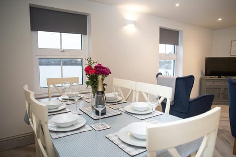 Dining area with table and six chairs, armchair and TV, windows with sea view