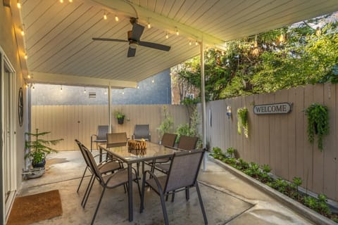 Covered patio w/ dining table, warm lighting & cozy seating for relaxed evenings outdoors