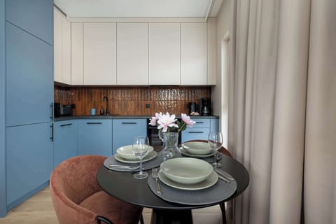 The neatly set table positioned next to the kitchen blends the comfort of home cooking with the pleasure of sharing a meal.