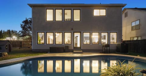Two-story house with illuminated windows and backyard pool.