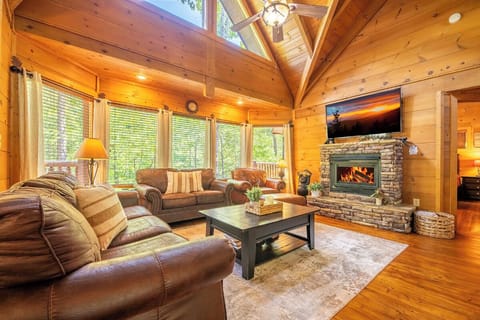 Sink into plush leather seating beside your crackling stone fireplace while cathedral ceilings and sunlight through tall windows create your perfect mountain retreat sanctuary.