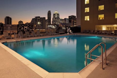 Rooftop pool with lounge chairs and city views at sunset