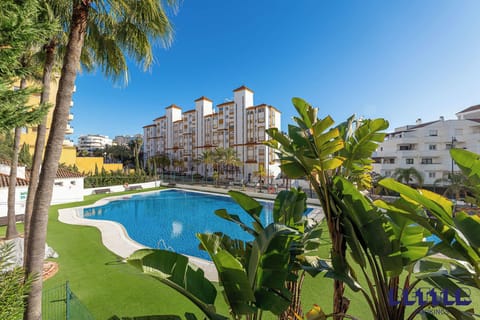 Residential complex with pool, palm trees, and lush lawns. Vibrant, sunny retreat blends leisure with tropical charm.