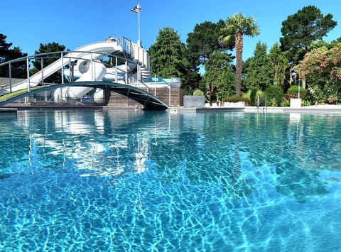 The tranquil surface of the swimming pool reflects the clear skies, inviting guests to slide down into its refreshing waters.