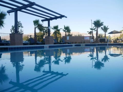 Peaceful pool with palm trees and lounge chairs by the mountain view
