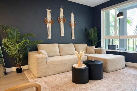 Spacious living room featuring a cozy L-shaped sofa, a full-size air mattress, and a 65" Smart TV with preloaded access to Netflix, Hulu, and Disney+, all set up for your enjoyment.