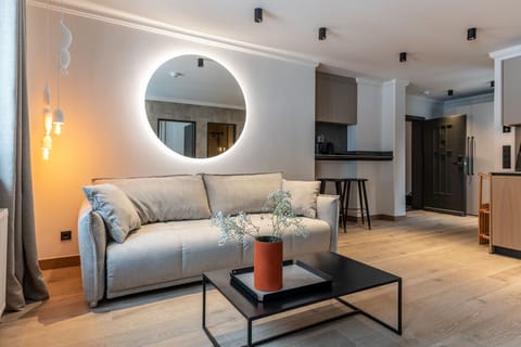 Offener Wohnbereich mit Sofa, Rundspiegel und Küche.