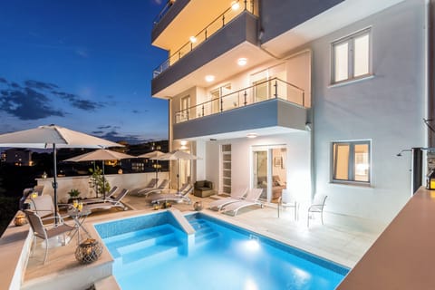 Outdoor pool with sun loungers during nighttime.