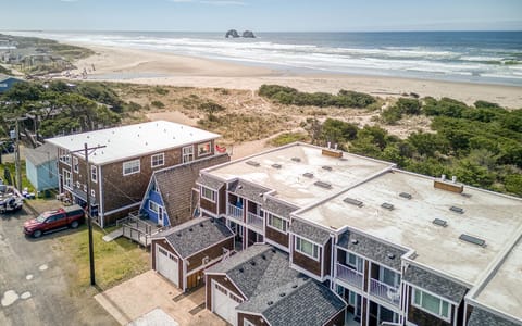 Beachfront property complex positioned steps from pristine sandy shores with dramatic offshore rock formations and rolling waves.