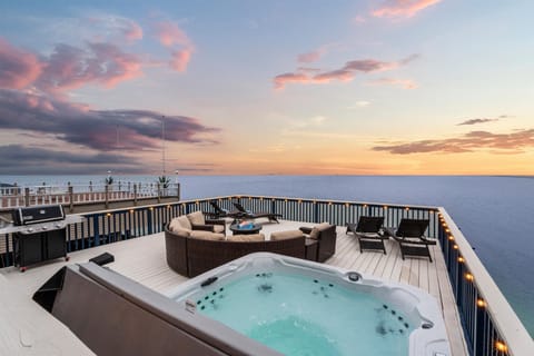Private hot tub on deck with surrounding seating and sunset sky backdrop, highlighting premium outdoor amenity for relaxation with stunning waterfront views in Jamaica Beach Texas.