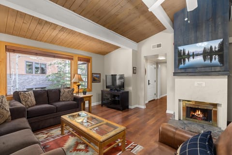 Settle into this warm living space where exposed beams and crackling fireplace create your perfect mountain retreat atmosphere.