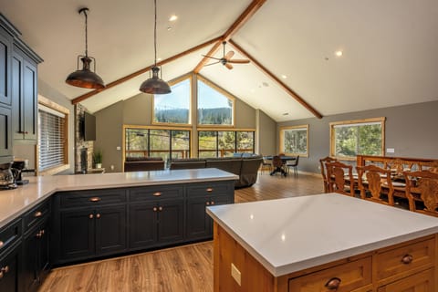 Soaring vaulted ceilings with exposed beams draw your eye to stunning forest views The open kitchen, dining, and living spaces invite you to cook, gather, and relax in style.