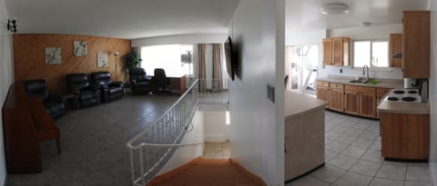 Panoramic shot of the living room, stairwell and kitchen, seen from the hallway.