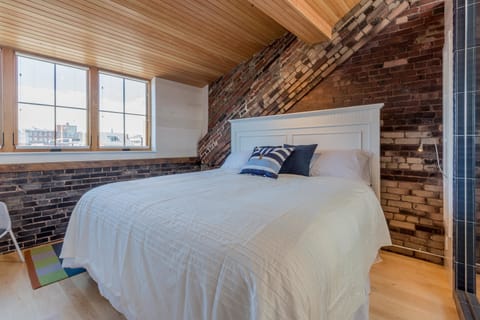King bed with beautiful wood ceilings and exposed brick walls.