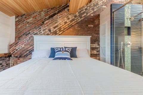 King bed with beautiful exposed brick and finished wood ceiling.