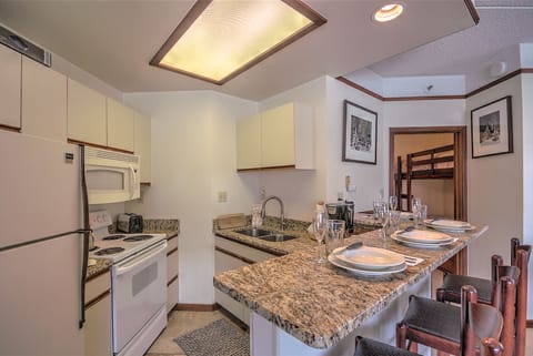 Close-up of granite eating counter / bar with four (4) bar stools. Full kitchen.