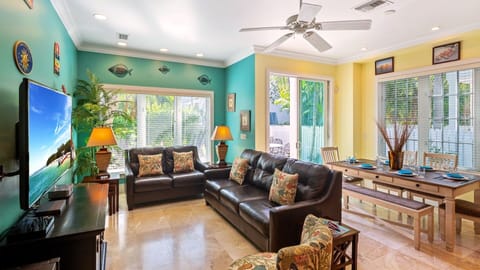 The living area has bright, tropical colors, tall ceilings, and luxurious modern furnishings...