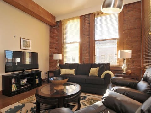 Cozy living room with exposed brick, comfortable lazy boy soda, and warm lighting!