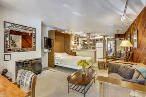 View from front entry over living room, queen Murphy bed, kitchen, eating area and hallway leading you to the bedroom with private deck.