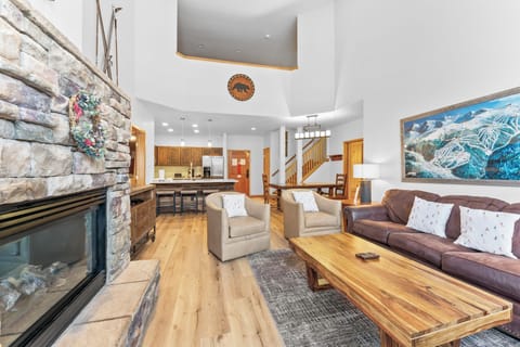 Spacious living area including vaulted ceilings, stone fireplace, floor-to-ceiling windows, and a queen sleeper sofa.