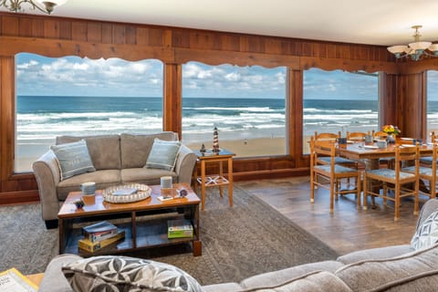 Living room and dining area overlooking the surf and sand. - Large windows overlooking the oceanfront in Roads End neighborhood.   Nice roomy open floor plan to enjoy kids playing in the sand or whale & storm watching.