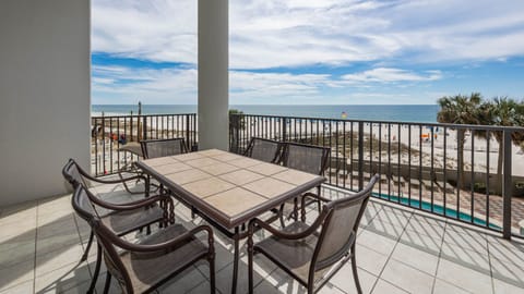 The balcony area features a tiled table and chairs, loungers, and a second floor beachfront view over the pool area
