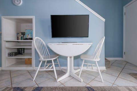 This cozy nook features a wall-mounted TV and a charming round table with two white chairs, perfect for meals or games