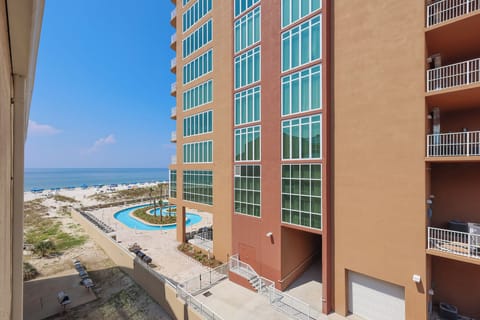 This view showcases a vibrant pool area surrounded by palm trees, with beach access just steps away