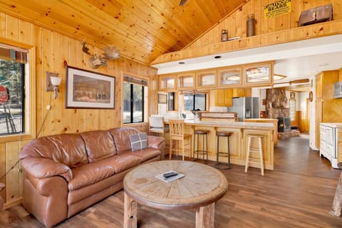 Cozy cabin living room with a stone fireplace, comfy seating, and a TV with an amazing view to the lake—perfect for relaxing evenings, movie nights, and unforgettable mountain getaways.