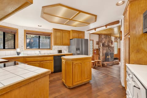 A beautiful spacious kitchen with a refrigerator, stove, microwave, oven, toaster, coffee machine, blender, dishwasher, and breakfast bar to enjoy a delicious meal.