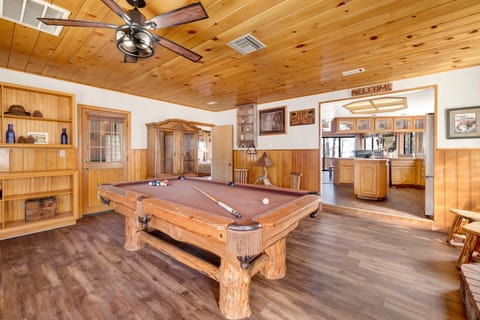 Rustic mountain cabin game room with a full-size pool table, cozy seating, and warm natural light—perfect for relaxing nights, friendly games, and unforgettable cabin stays.