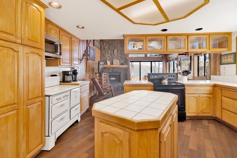 A beautiful spacious kitchen with a refrigerator, stove, microwave, oven, toaster, coffee machine, blender, dishwasher, and breakfast bar to enjoy a delicious meal.