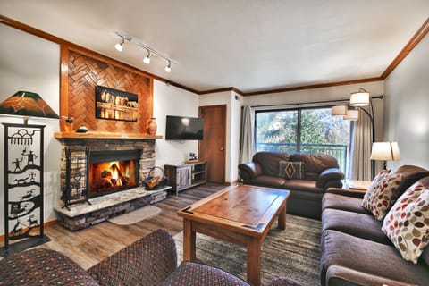 Cozy living room with wood burning fireplace, wall mounted TV, private patio