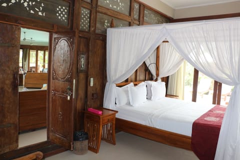 A wooden teak style bedroom at ground floor with pool and garden view