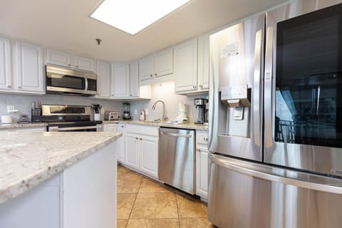 Bright kitchen featuring white cabinetry, granite countertops, stainless appliances, and a coffee station 