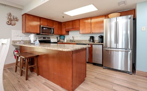 The kitchen features rich wood cabinetry, granite countertops, stainless appliances, a Keurig and a coffee maker