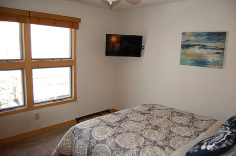 Guest bedroom with 32" flat screen TV and wooden window blinds.
