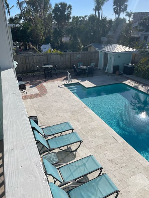 Pool deck has 7 lounge chairs and 13 chairs surrounding 3 tables. 