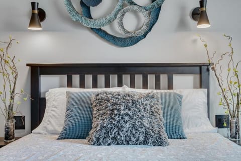 The Serenity Suite is fashionably appointed with cool, relaxing hues of blue and gray. The private bedroom features a comfy queen bed, a wardrobe, and a smart TV.