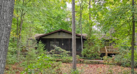 Nestled in the woods - view from lake to house. Deck on left of screen porch.