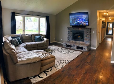 Livingroom with leather sectional, gas fireplace, and 65” 4K HDTV