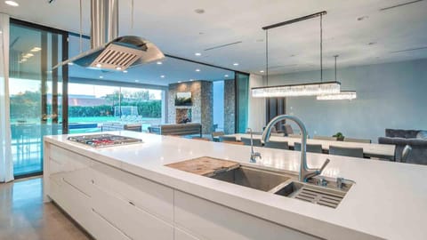 Modern kitchen with white island, stainless hood, and open layout.
