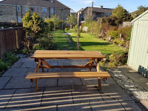 Back garden with slabbed patio area and picnic bench